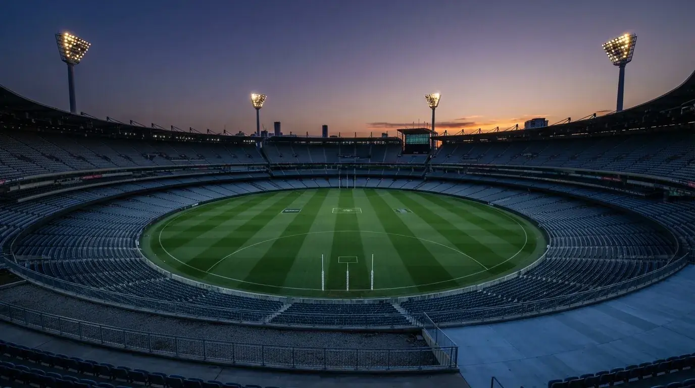 An empty football stadium with floodlight masts at dusk