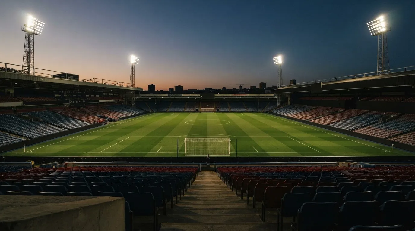 An empty football stadium with floodlight masts at dusk