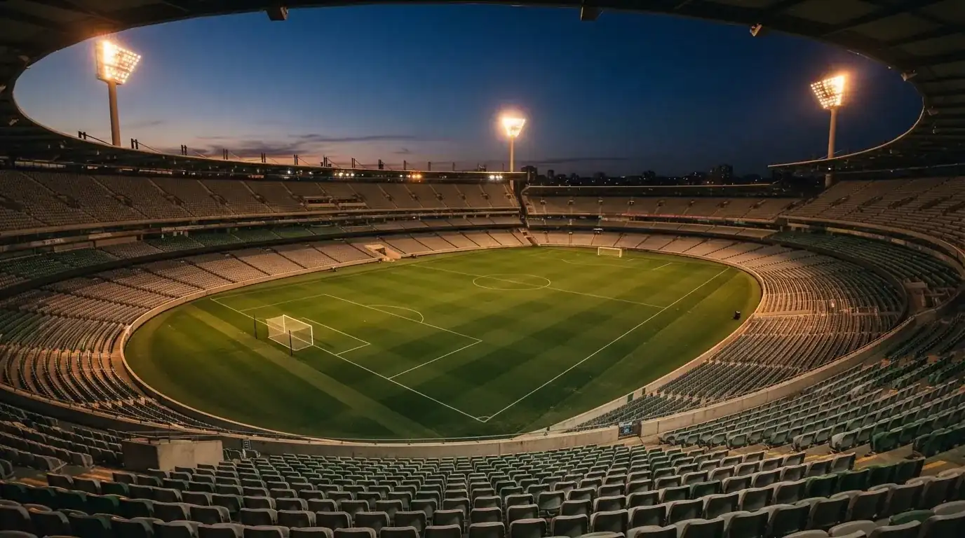 An empty football stadium with floodlight masts at dusk
