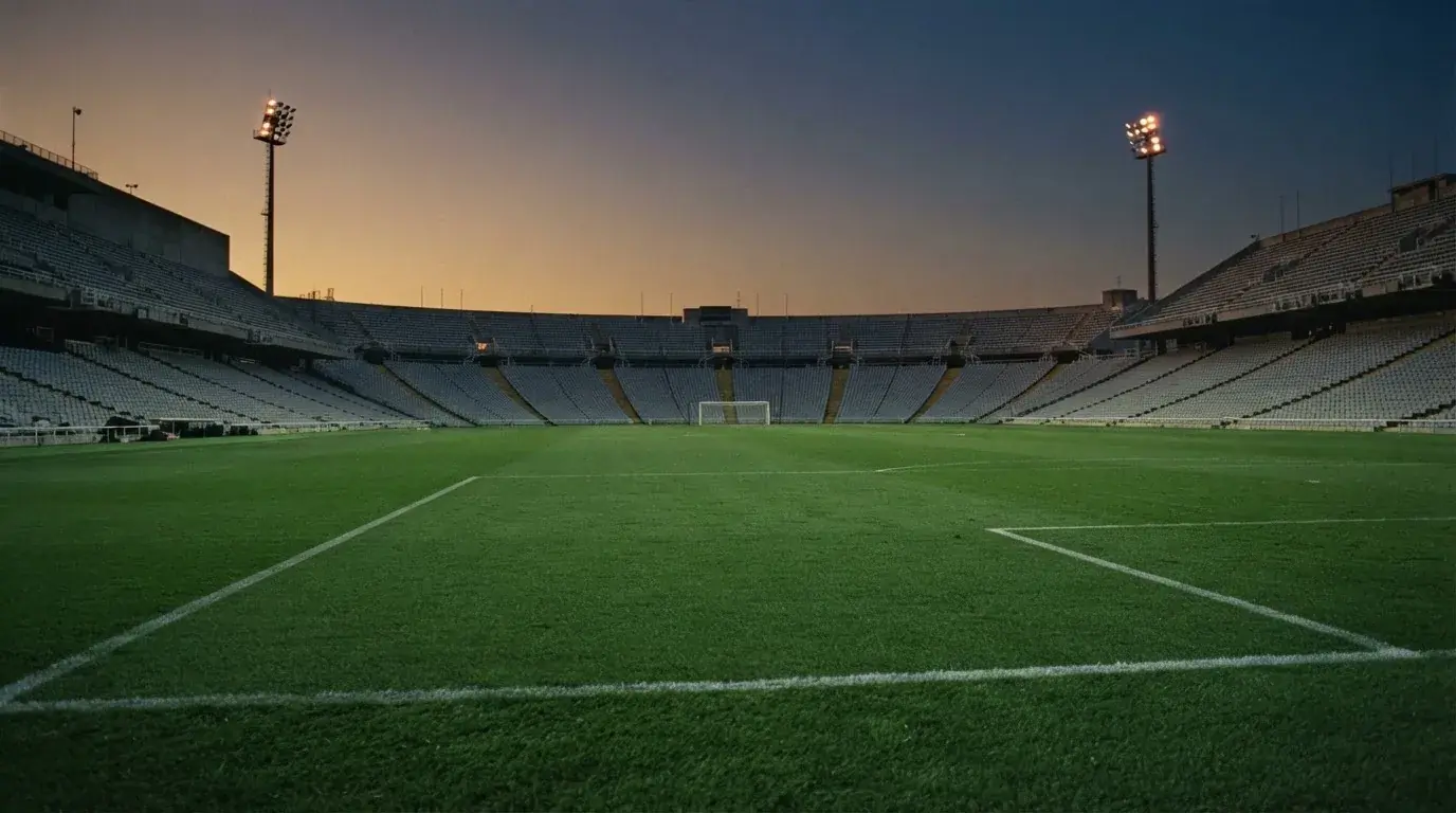 An empty football stadium with floodlight masts at dusk