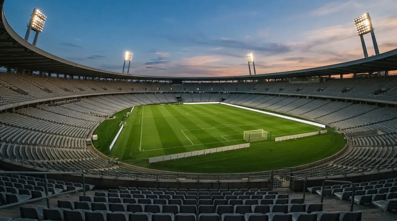 An empty football stadium with floodlight masts at dusk