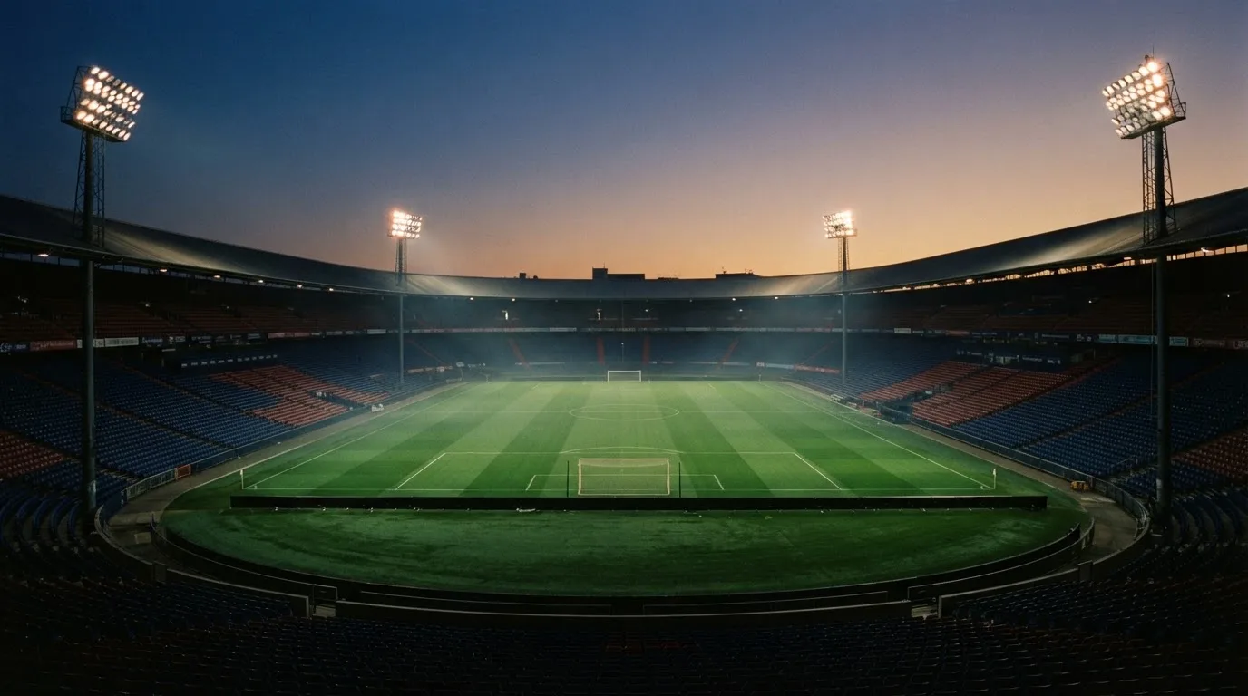 An empty football stadium with floodlight masts at dusk