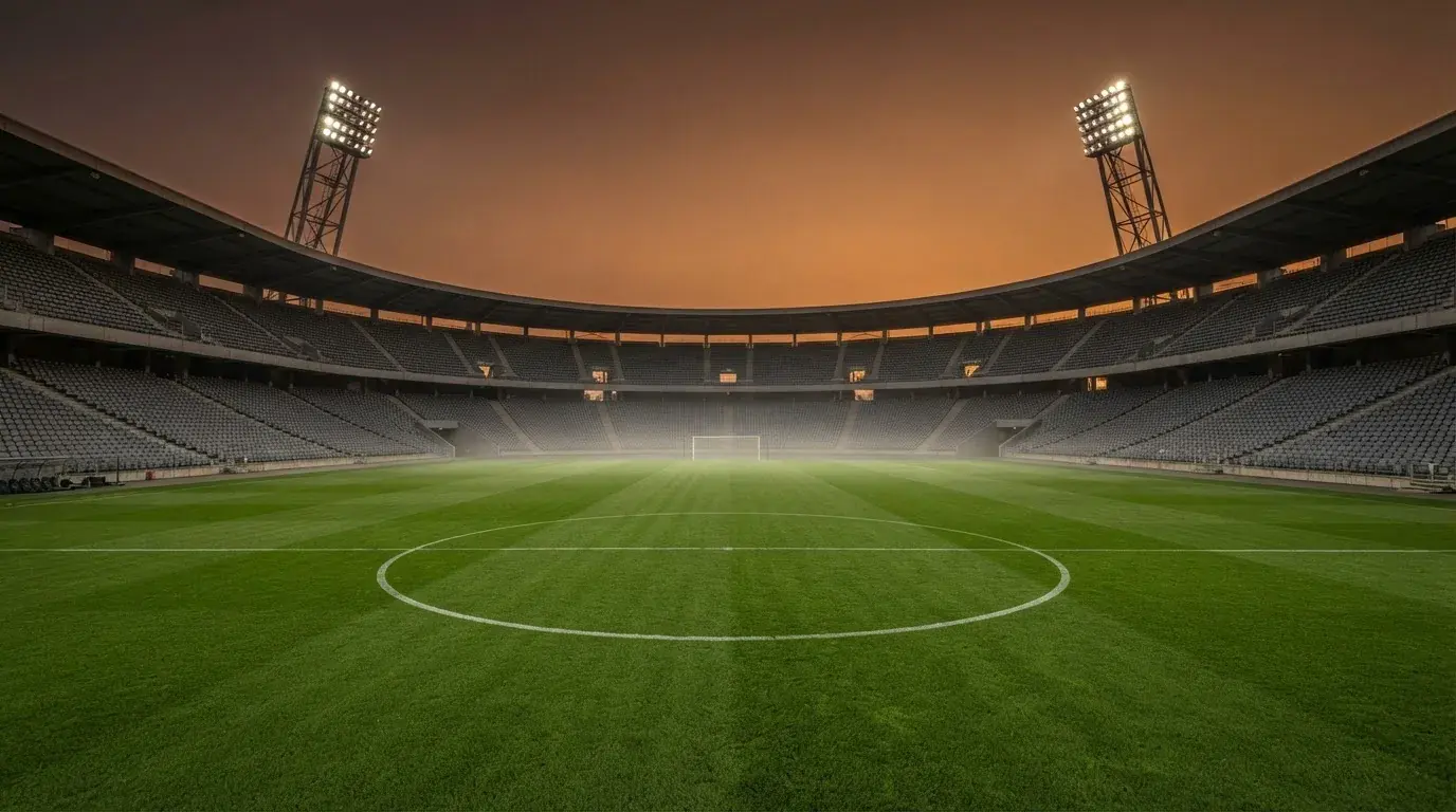 An empty football stadium with floodlight masts at dusk