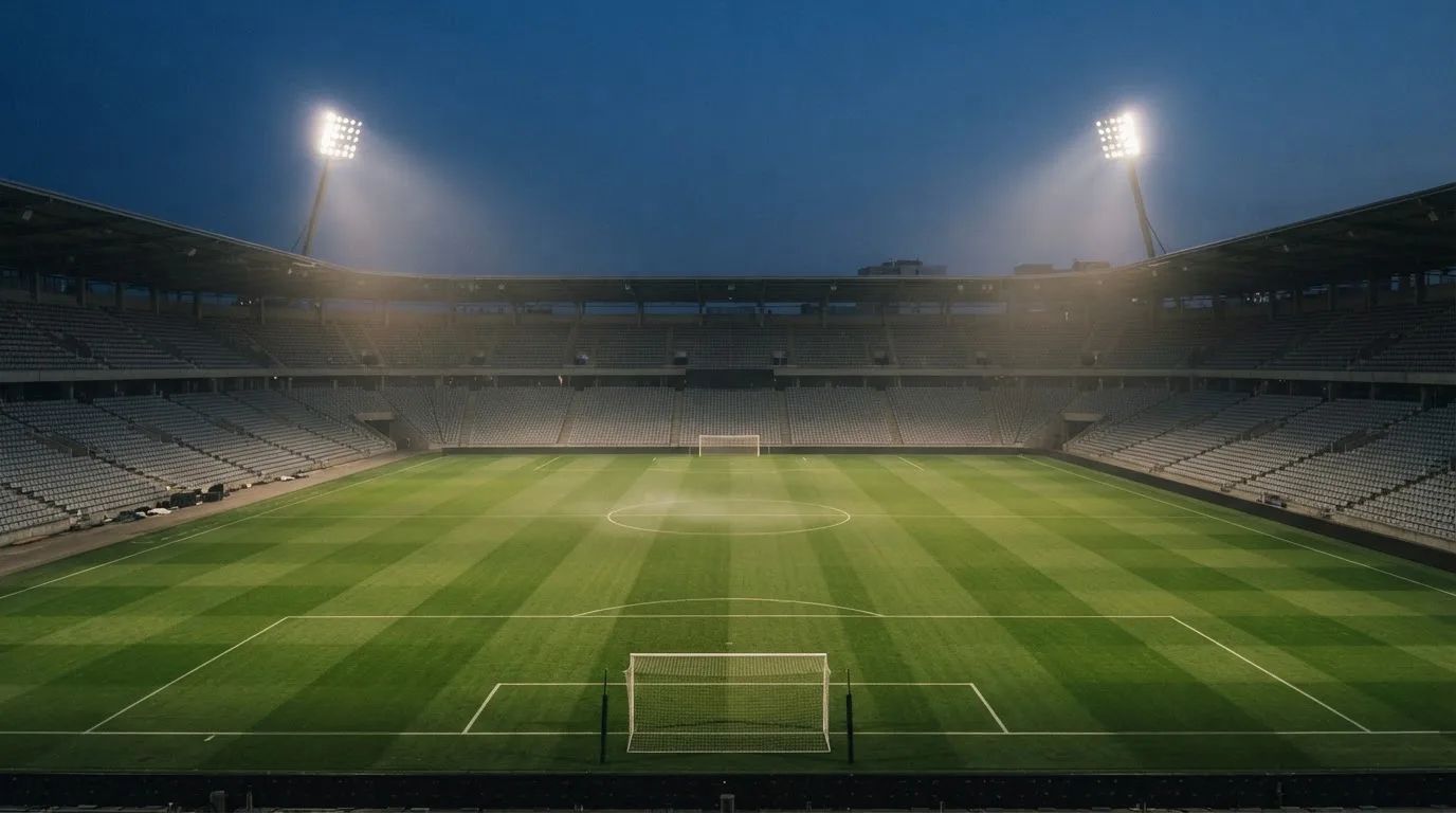 An empty football stadium with floodlight masts at dusk