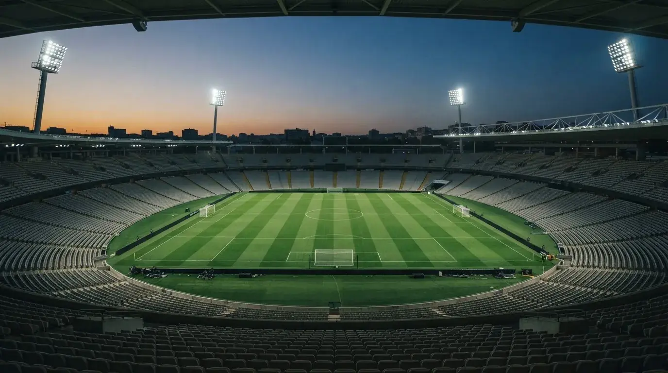 An empty football stadium with floodlight masts at dusk