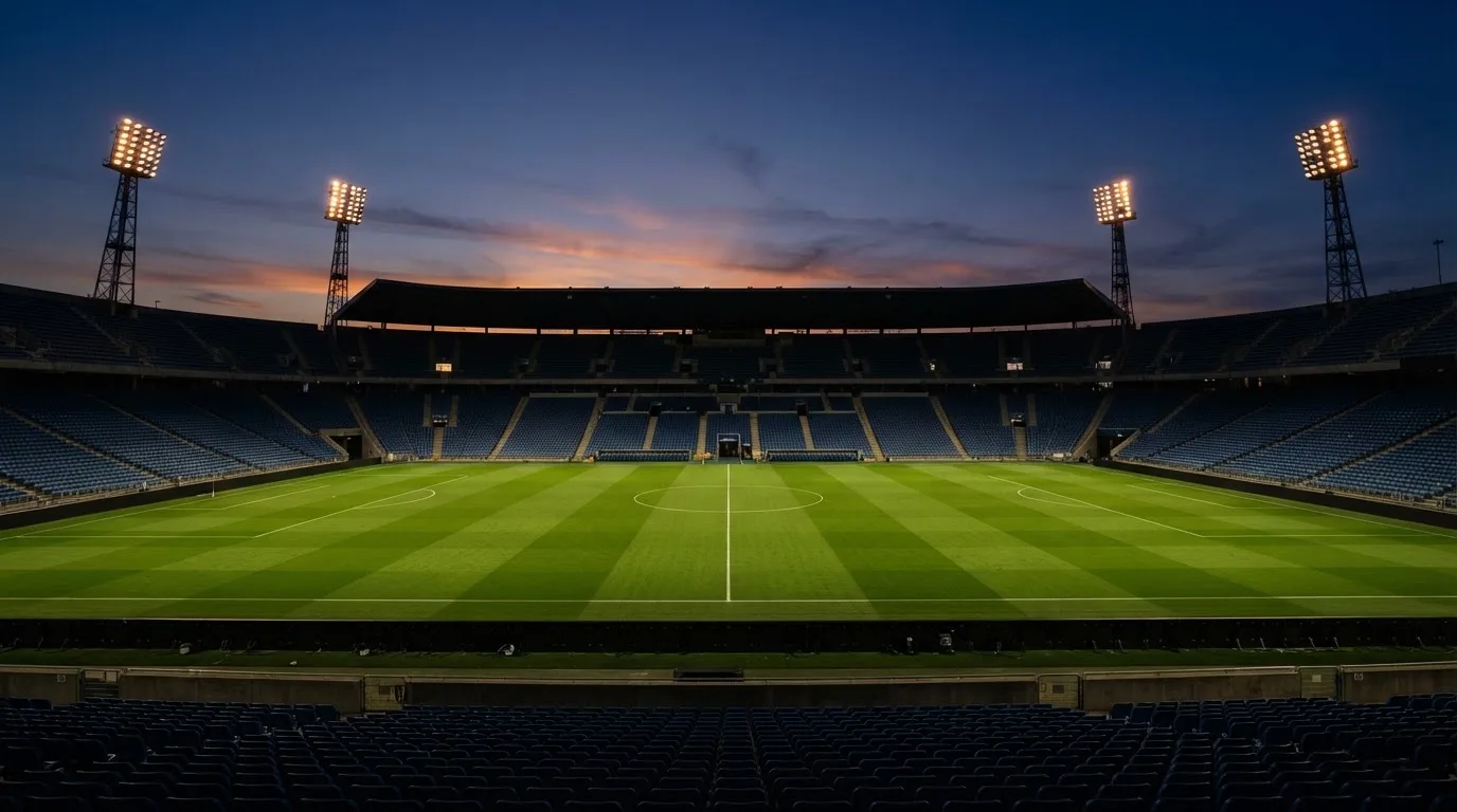An empty football stadium with floodlight masts at dusk