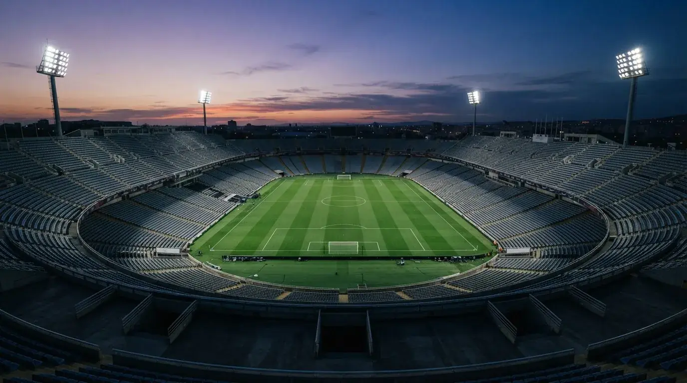 An empty football stadium with floodlight masts at dusk