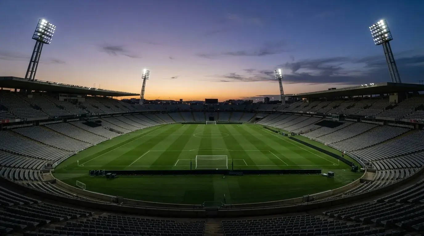An empty football stadium with floodlight masts at dusk