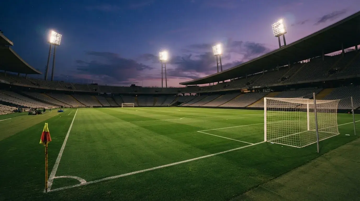 An empty football stadium with floodlight masts at dusk