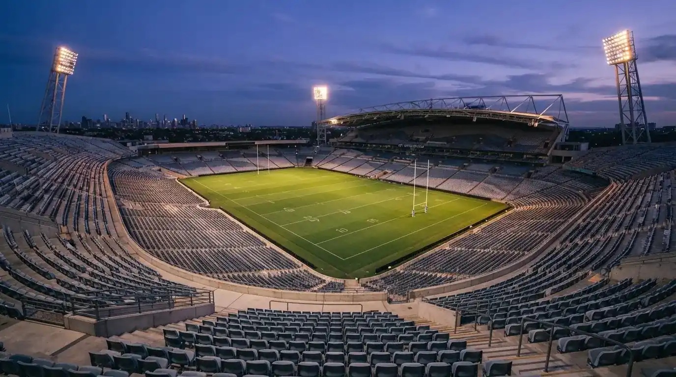An empty football stadium with floodlight masts at dusk