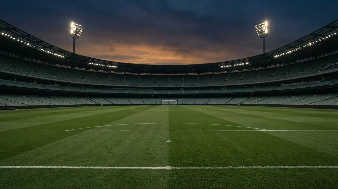 An empty football stadium with floodlight masts at dusk